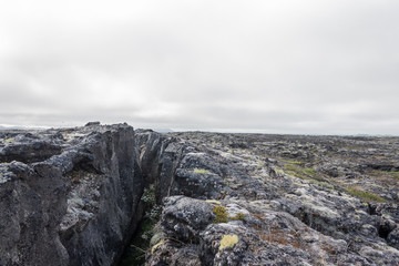 Crack in the ground after strong earthquake, rift in grey rocks, lava field