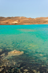 Turquoise, cyan geothermal spring lagoon in the desert with orange sand dunes, Iceland