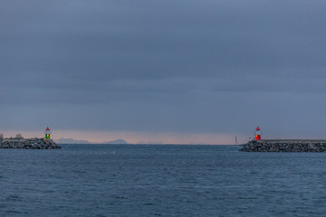 Traveller enjoying the Lofoten mountains landscape with lighthouse on a gray rainy day