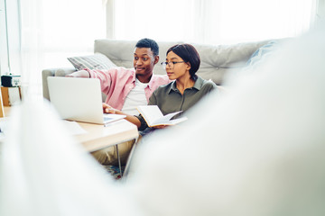 Positive african american couple  making shopping on laptop computer browse web page at home interior , positive dark skinned family making video call using application on netbook at apartment.