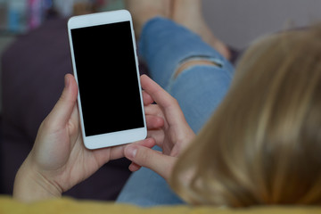  woman lies on a sofa and holds a white smartphone in her hands