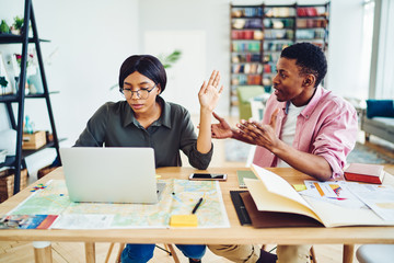 Angry african american colleagues having quarrel about disagreement while working together cooperating, serious dark skinned woman looking at laptop computer showing sign of irritation of man's talk .
