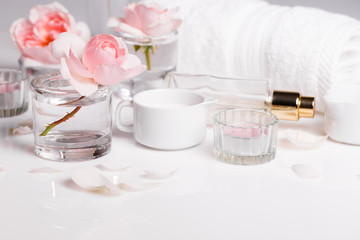 Spa sitting with pink rose ,salt, candles, towel, petals in white background.