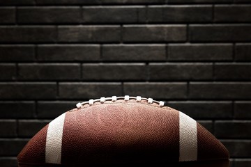 American football ball on dark stone background