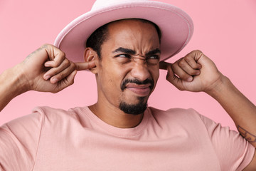 Photo of displeased african american man plugging her ears