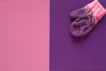Children's winter mitten is on a pink and purple background. Handmade.
