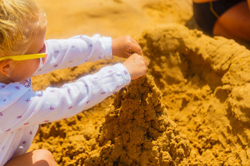 baby playing at the beach. child's hands close-up build top of sand castle, selective focus