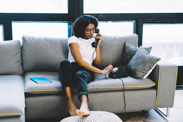 Stylish african american young woman in eyeglasses 20 years old dialing number on vintage black...