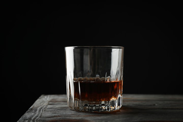 Glass of whiskey on wooden background, space for text