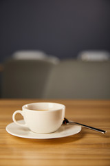 selective focus of white cup with hot coffee near spoon in cafe