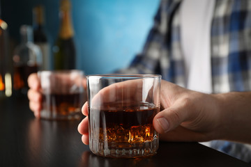 Men holding glasses of whiskey at the bar, space for text