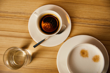 top view of cups with coffee near glass of water in cafe