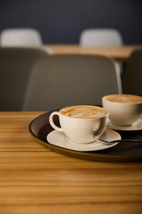 selective focus of cappuccino in white cups on black tray
