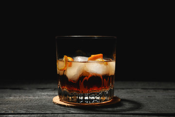 Glass of whiskey with orange peel on wooden background, space for text