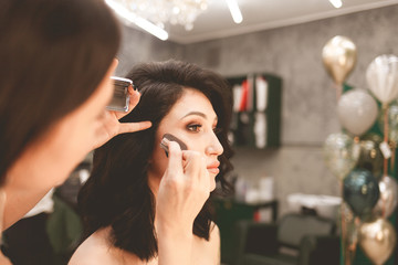 Make-up artist does makeup and applies powder to contour the face