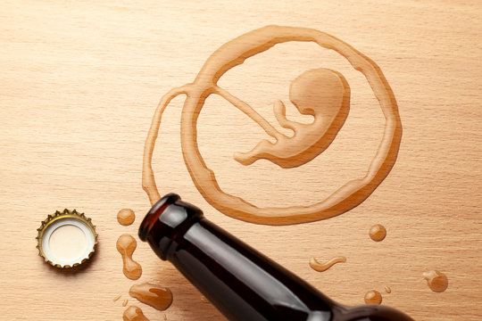 Alcohol and pregnancy. Bad habits. Beer bottle and spilled beer in the shape of an embryo