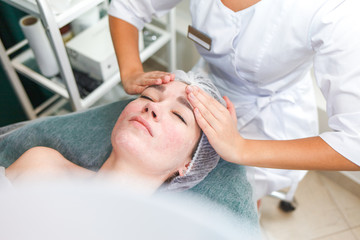 Doctor beautician makes cosmetic facial massage. Woman relaxes on a cosmetic chair