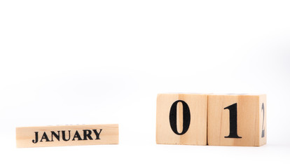 Closeup white wooden calendar with black 1 january word on  blurred white wood desk and White  color White in room textured background with copy space , selective focus at the calendar