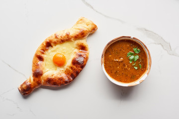 Top view of adjarian khachapuri and soup kharcho on marble texture