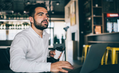 Contemplative male IT professional pondering on program code for public website with banking system, pensive skilled man in formal shirt thinking on idea for software developing startup project