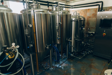 Microbrewery equipment. Close up tanks in brewery warehouse. Metal brewery vessels. Small business concept.