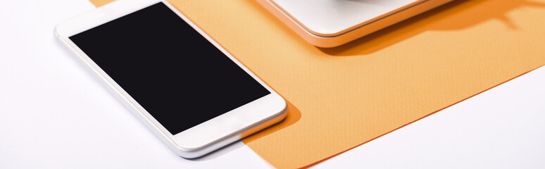 panoramic shot of smartphone with copy space and orange paper