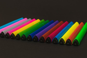 Colorful triangular markers lie in a row on a black paper background. 