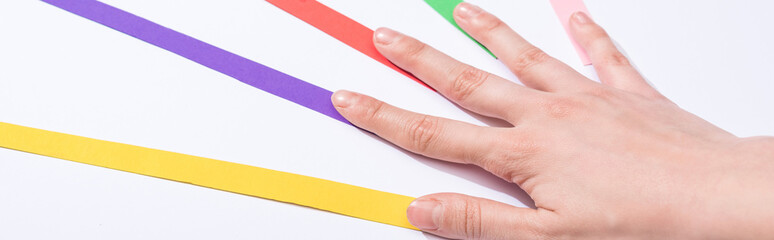 panoramic shot of woman touching colorful paper strips on white background