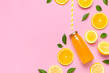 Flat lay composition with glass bottles of juice or fresh, slices of fresh lemon and orange, green leaves, cocktail tubes on pink background top view copy space. Citrus Juice Concept Vitamin C Fruits