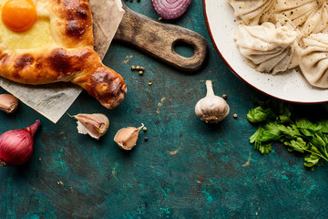 top view of delicious khinkali, Adjarian khachapuri on green background