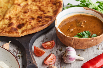 Imereti khachapuri and soup kharcho with spices and vegetables on table