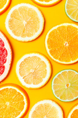 Flat lay composition with slices of fresh lemon orange grapefruit lime on yellow background top view. Citrus Juice Concept, Vitamin C, Fruits. Creative summer background. Close-up fruit pattern