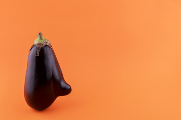 Ugly eggplant with a nose on a orange paper, minimalism
