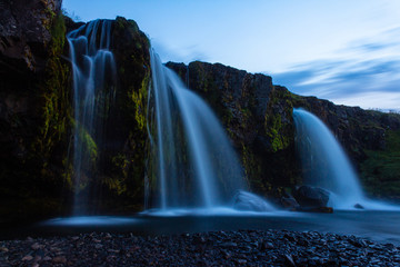 Fototapeta na wymiar Waterfall in the mountains, long exposure photo, high big tall waterfall, Iceland Kirkjufellsfoss