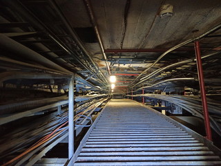 Dark underground tunnel with high-voltage wires laid in iron trays.