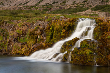 Obraz premium Cascade waterfall, moss stone, river falling down the slope of a hill into a lake