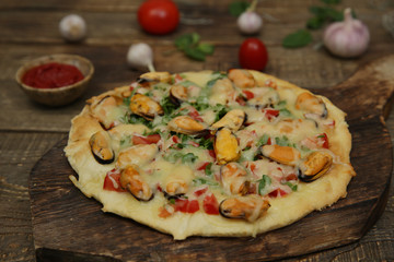 seafood pizza with mussels and mozzarella cheese isolated on a wooden board and on a wooden rustic table. Mediterranean food. Vegetarian. Close-up.