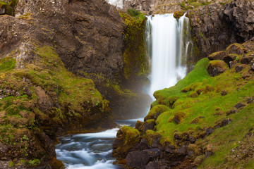Small waterfall in the mountains with the river moss stone 