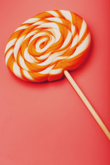 Orange Lollipop on a pink background with a soft contrast. Minimal concept with copy space.