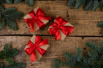 Three christmas gift boxes with red bow on aged textured wooden background, with place for design or text.