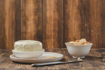 Cheese and cracker in a white bowl on a wooden background. Copyspace.