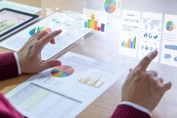 Businessman interacts with augmented reality graphics while deeply reviewing a financial report for...
