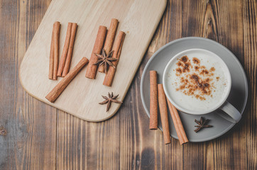Eggnog. Traditional christmas cocktail in a mug and cinnamon sticks and anise on a white bowl on a wooden background. Top view