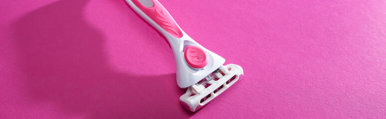 feminine razor on pink background with copy space, panoramic shot