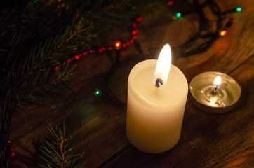 Christmas background or greeting card. Christmas candle, Christmas tree branch and decorations on dark wooden background. Top view with copy space.