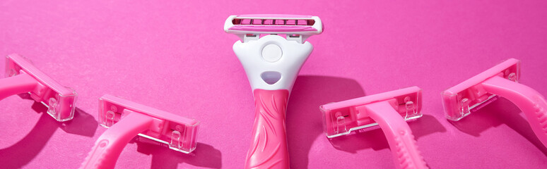panoramic shot of feminine razors on pink background