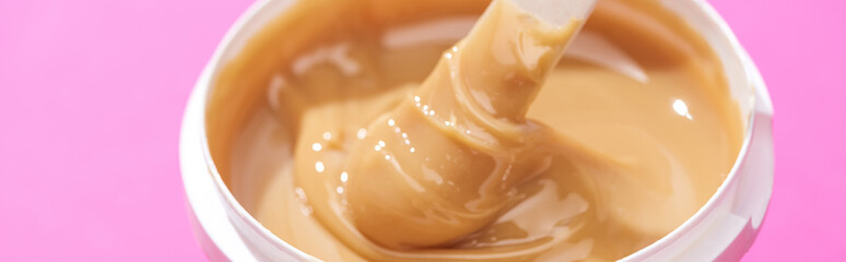 close up view of depilation wax in container with stick isolated on pink, panoramic shot