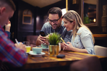 Attractive male showing something to his girlfriend while having a little coffee break.