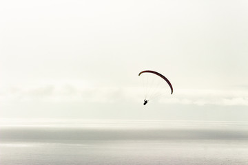 Paraglider in the sky doing tricks over the sea horizon, parachute