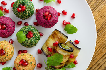 pkhali and badrijani  decorated with pomegranate seeds and coriander leafs on white plate placed on...